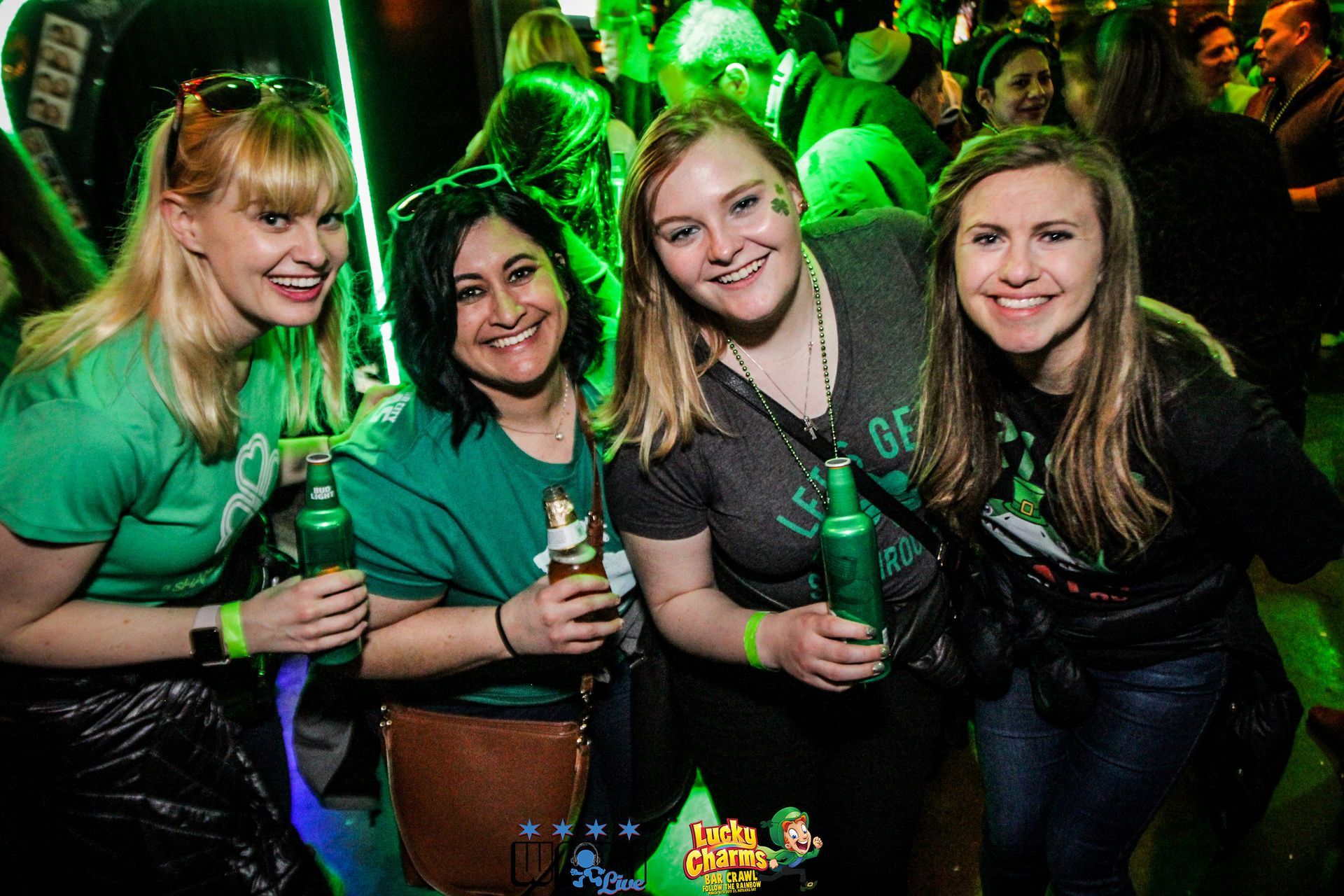 A group of women are posing for a picture while holding beer bottles.