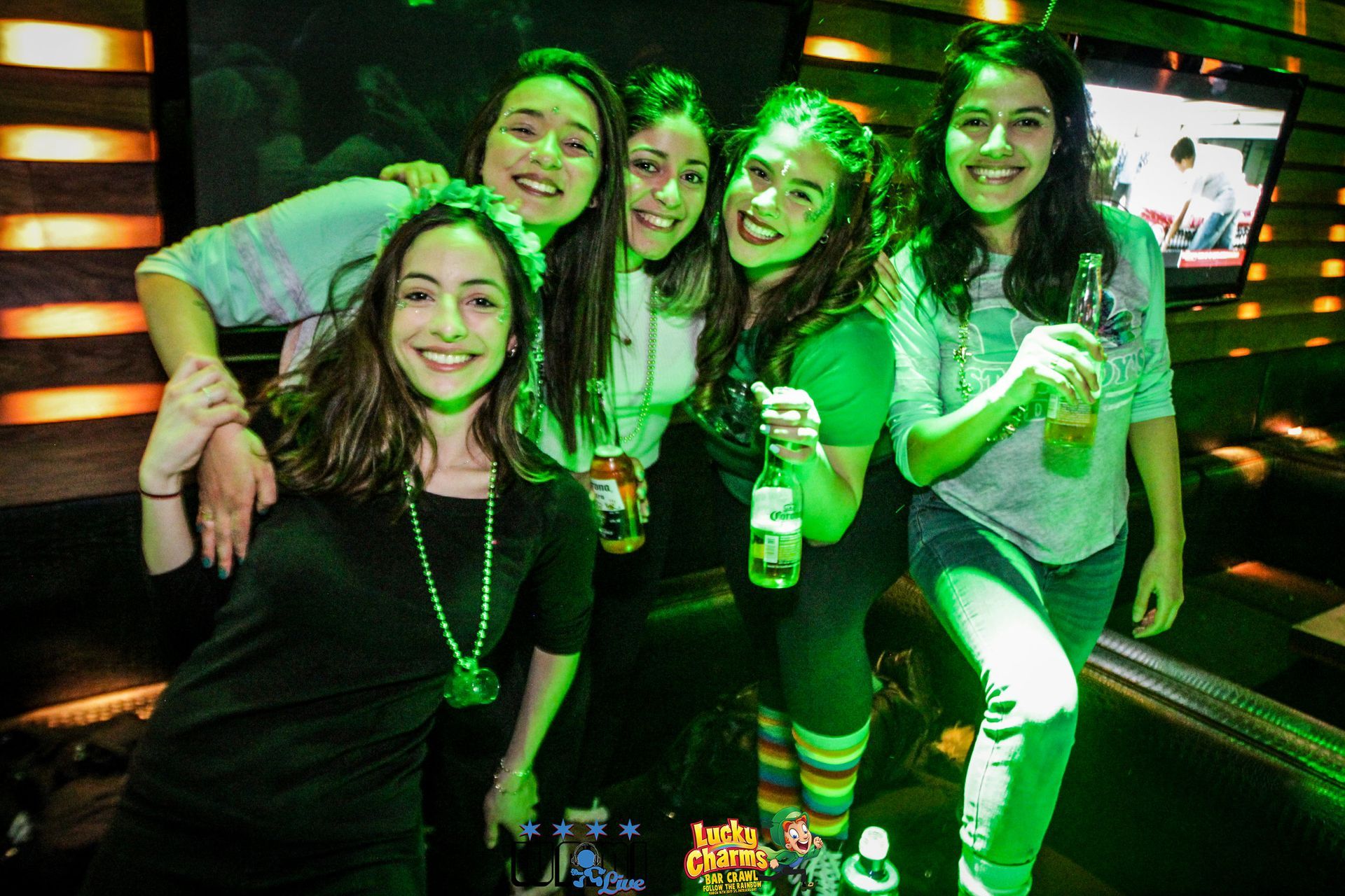 A group of young women are posing for a picture while holding beer bottles.