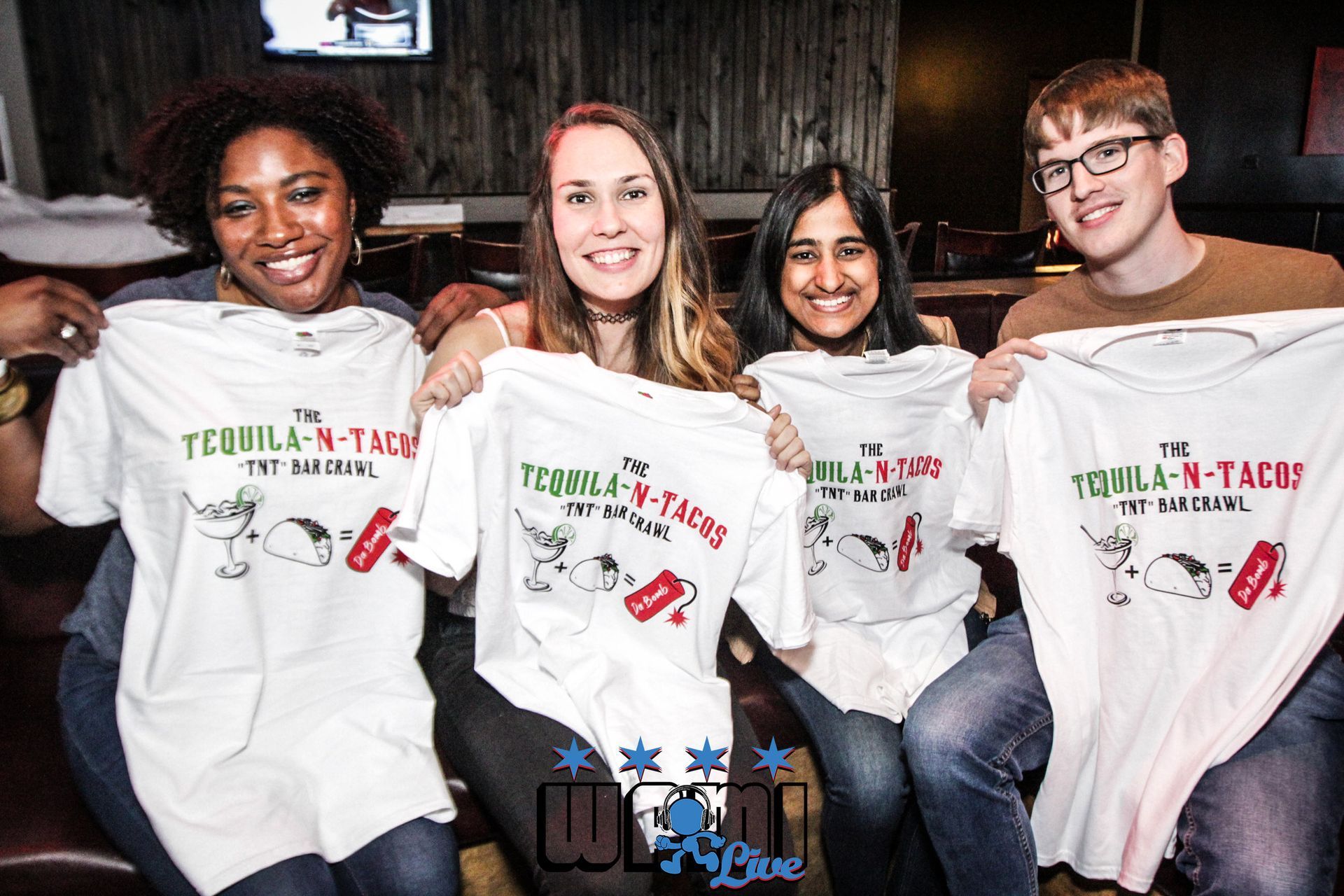 A group of people are holding up t-shirts that say tequila tacos.