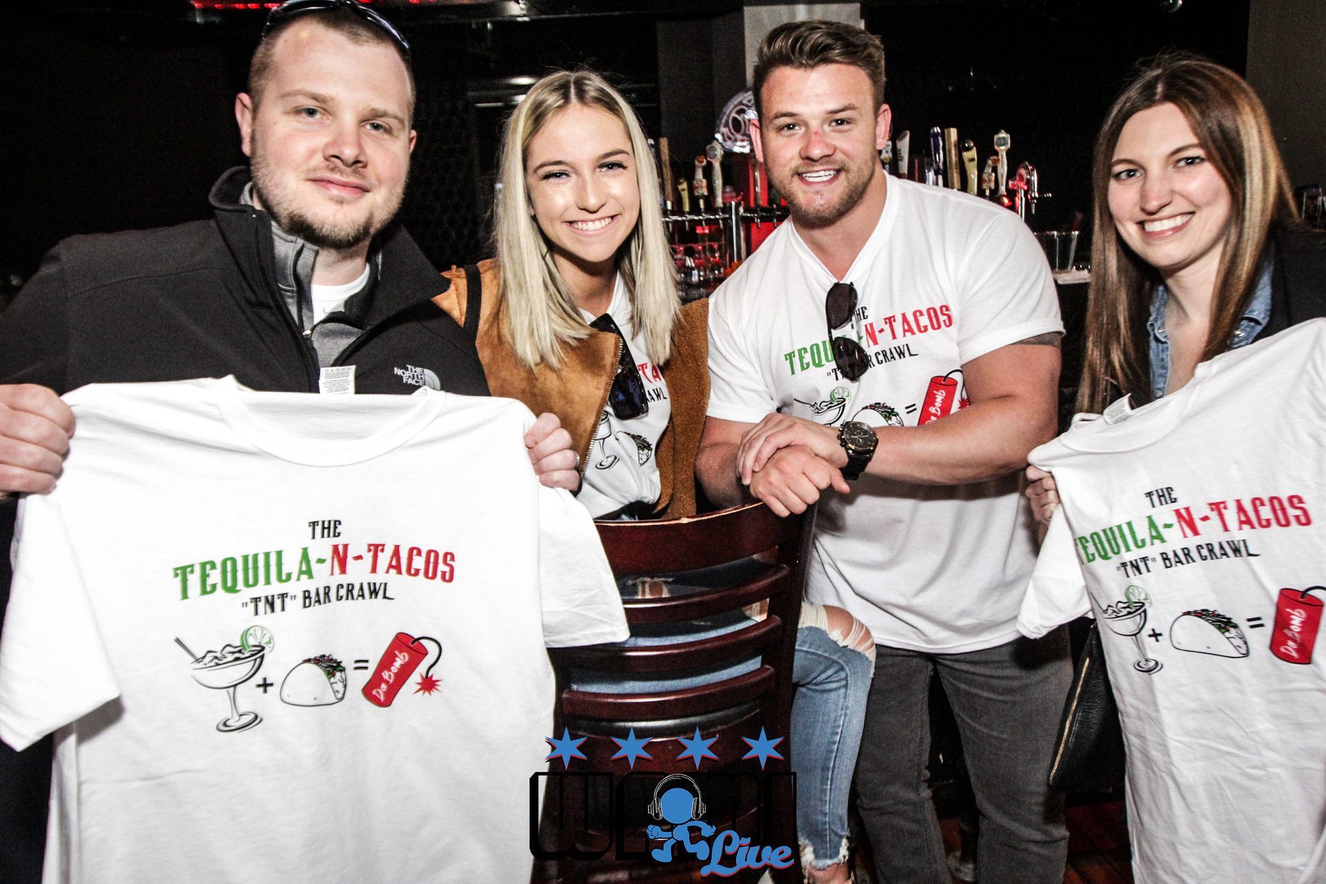 A group of people holding up t-shirts that say tequila n tacos