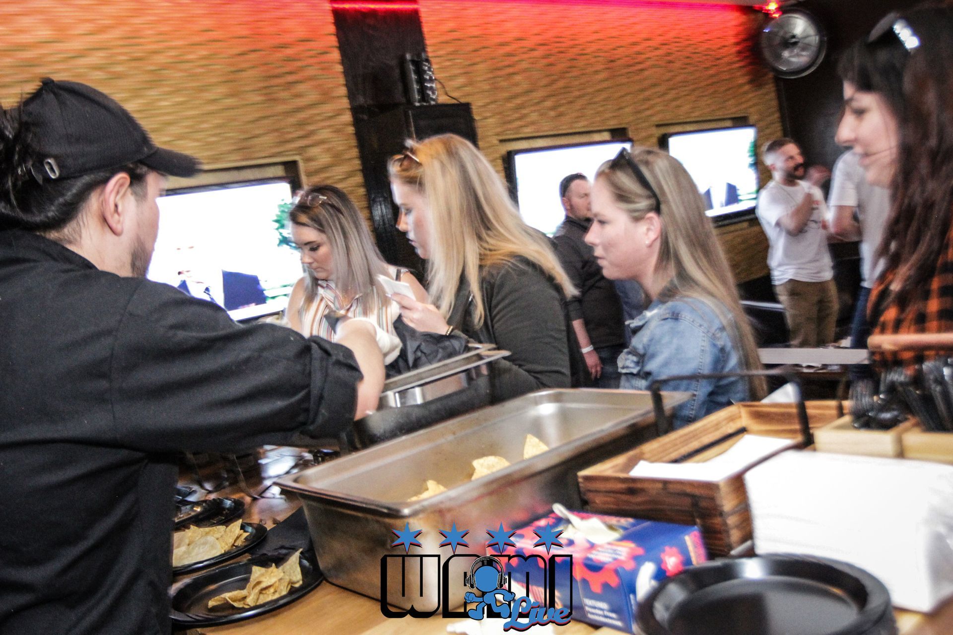 A man is serving food to a group of people in a restaurant.