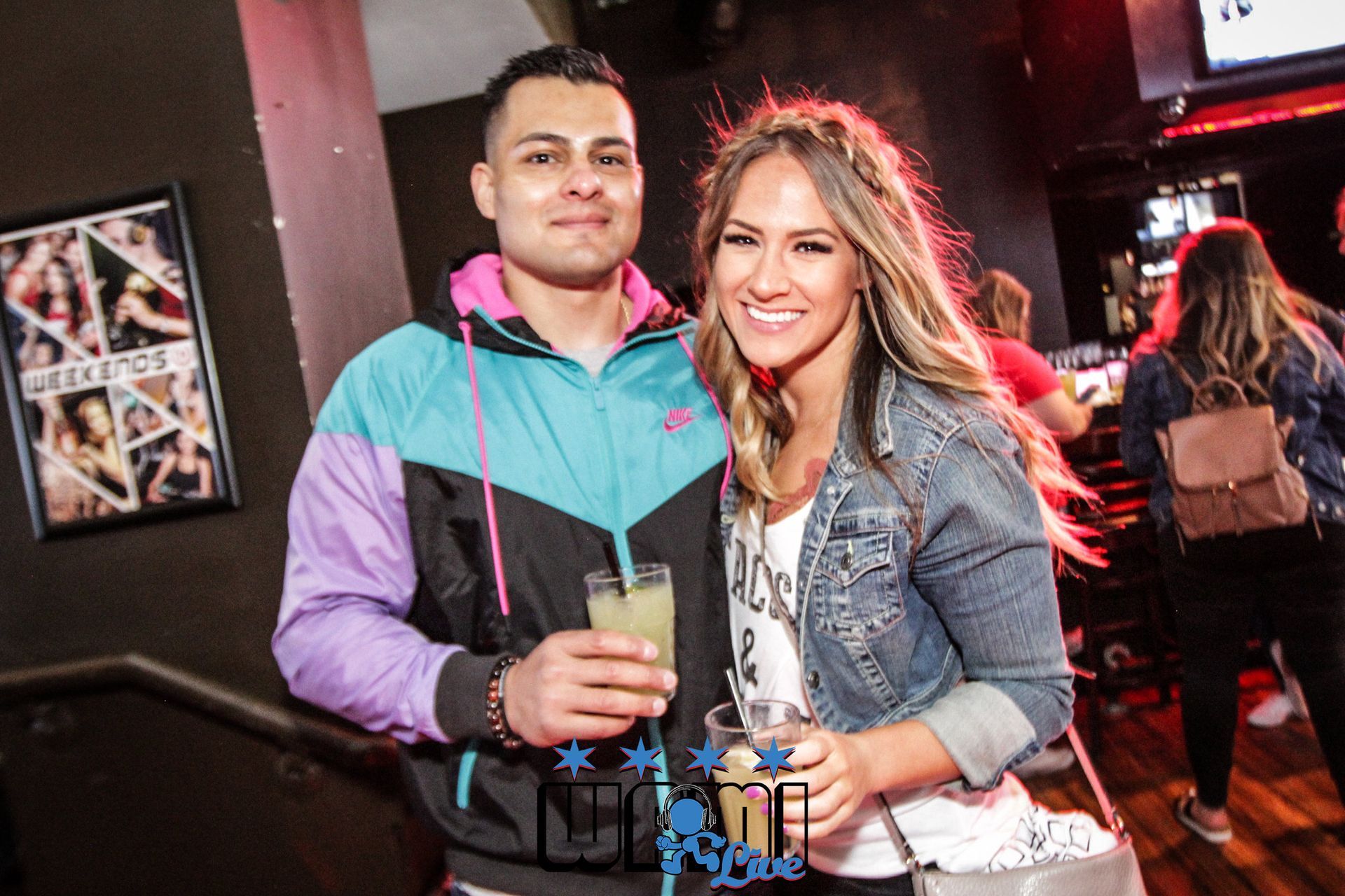 A man and a woman are posing for a picture while holding drinks.