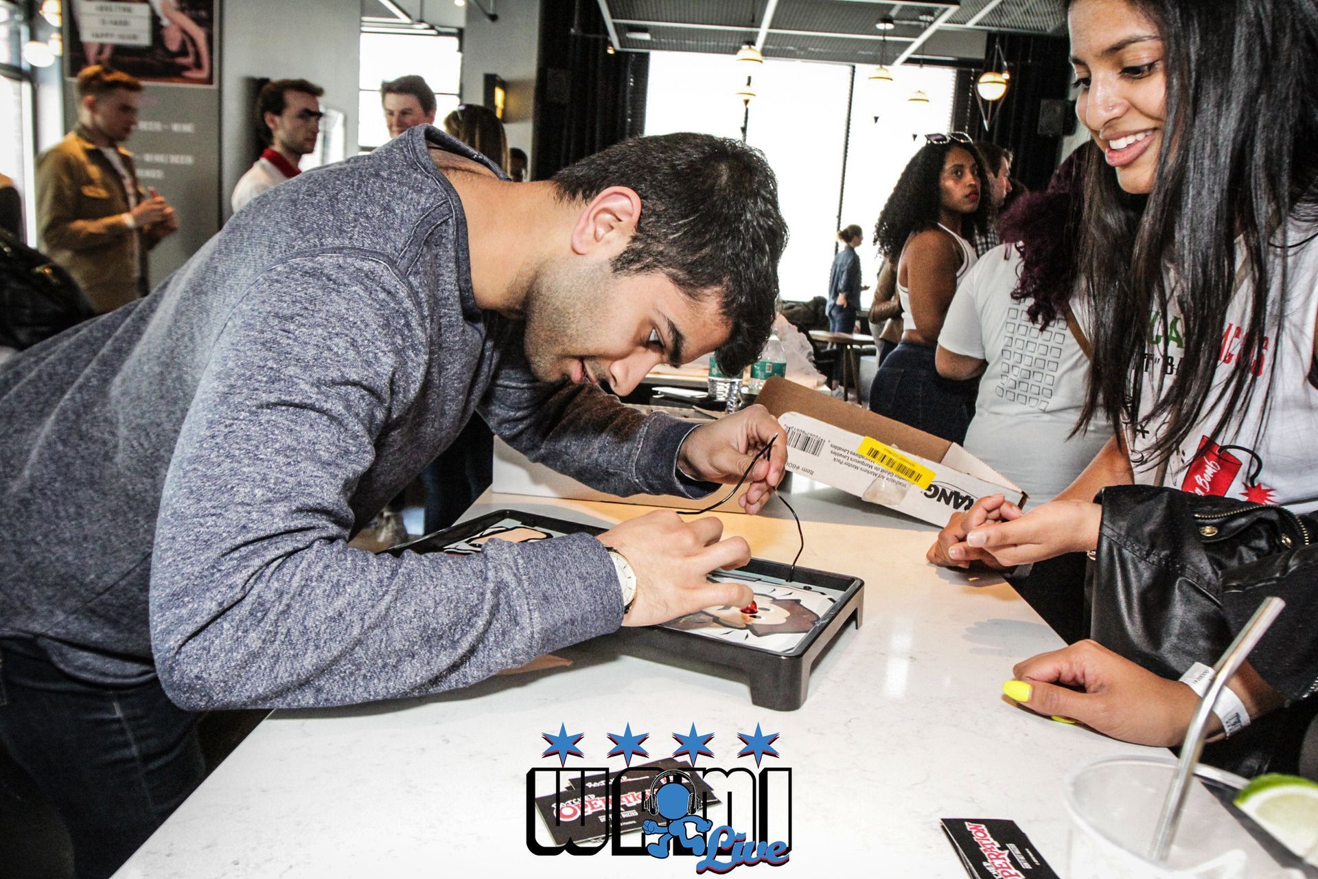 A man is signing a picture for a woman at a table