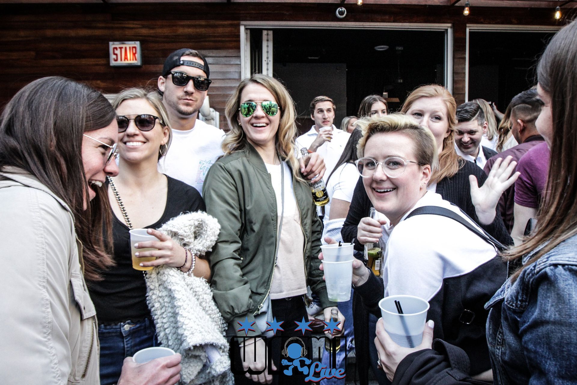 A group of people are standing in front of a building holding drinks.