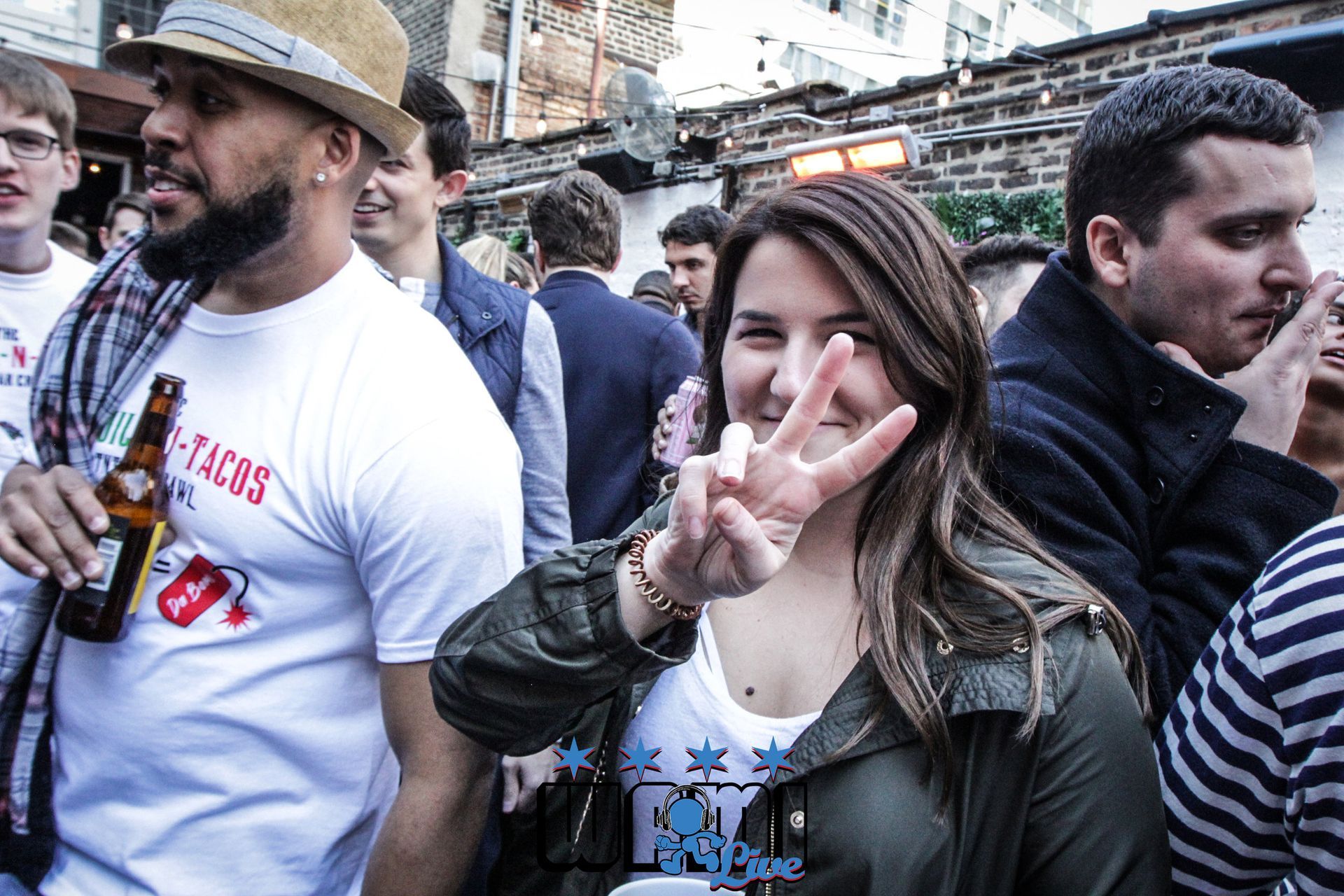 A woman is giving a peace sign in a crowd of people