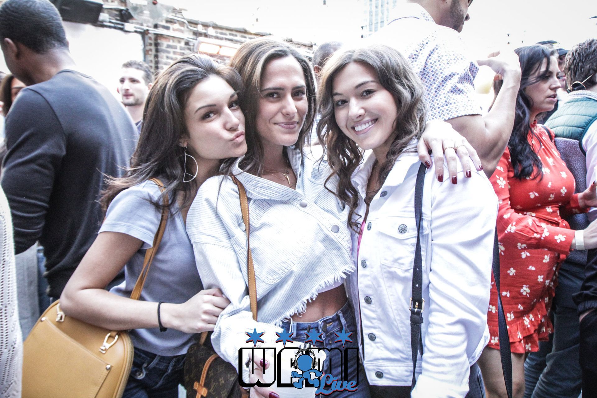 Three women are posing for a picture in front of a crowd.