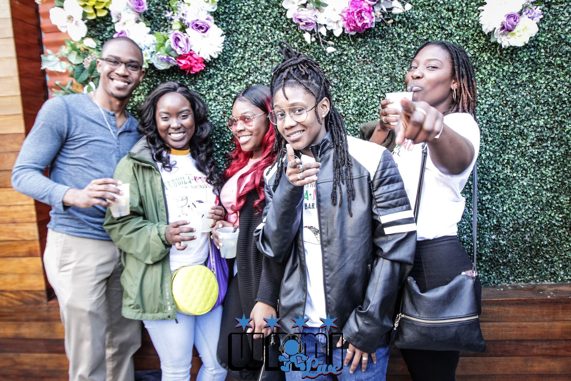 A group of people are posing for a picture in front of a flower wall.