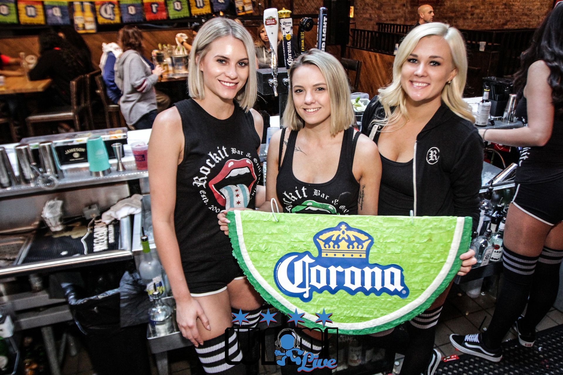 Three women are holding a sign that says corona on it.