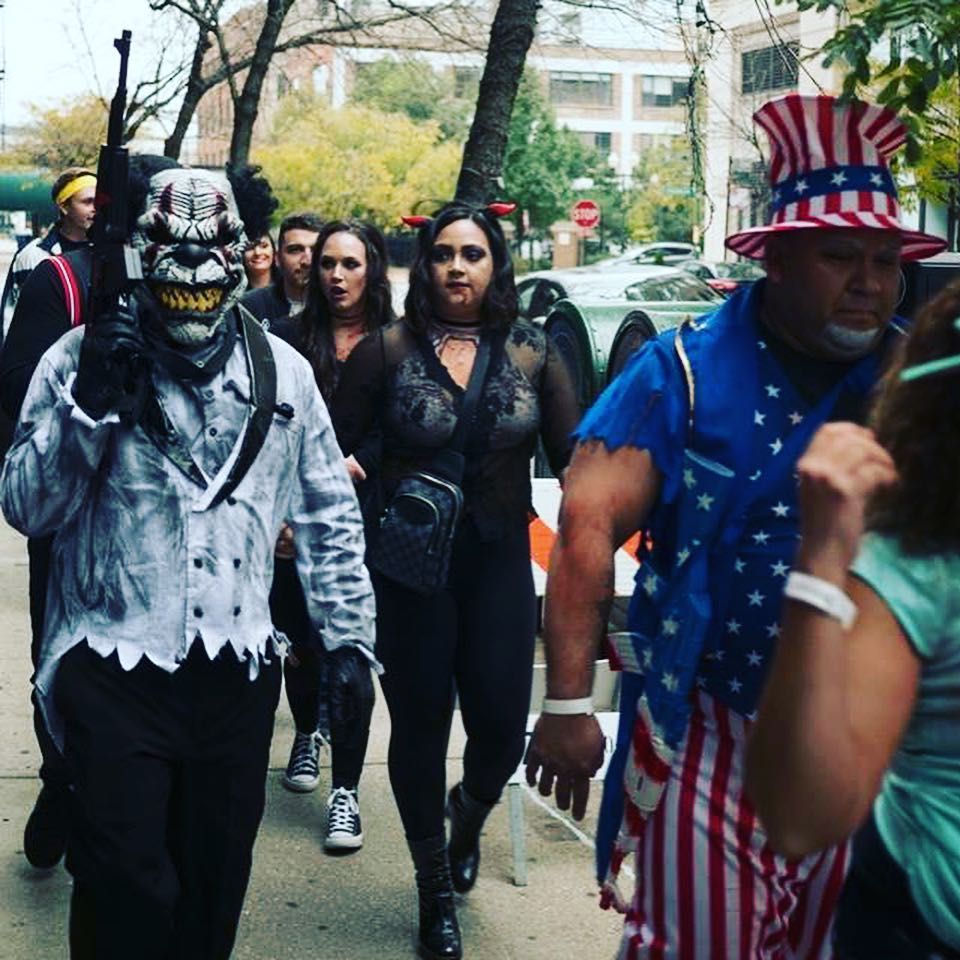 A group of people dressed in halloween costumes are walking down a sidewalk