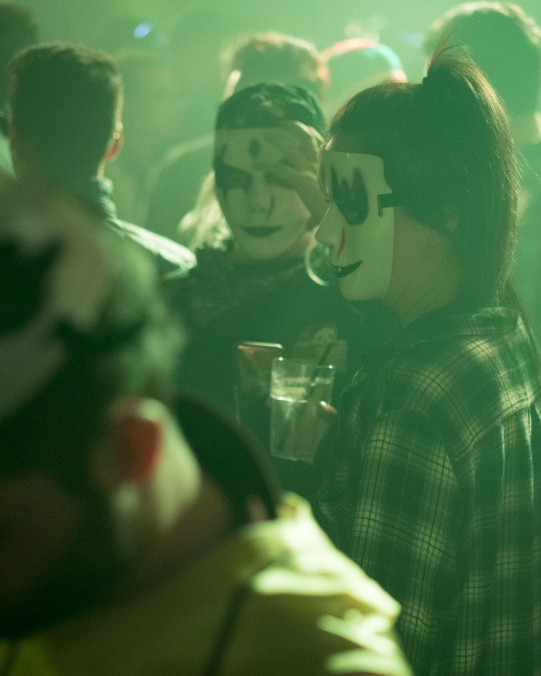 A group of people wearing masks are standing in a dark room.