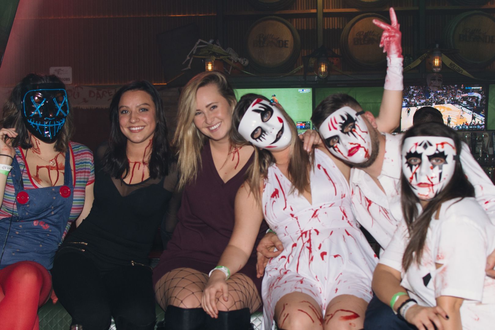 A group of people wearing halloween costumes and masks are posing for a picture.