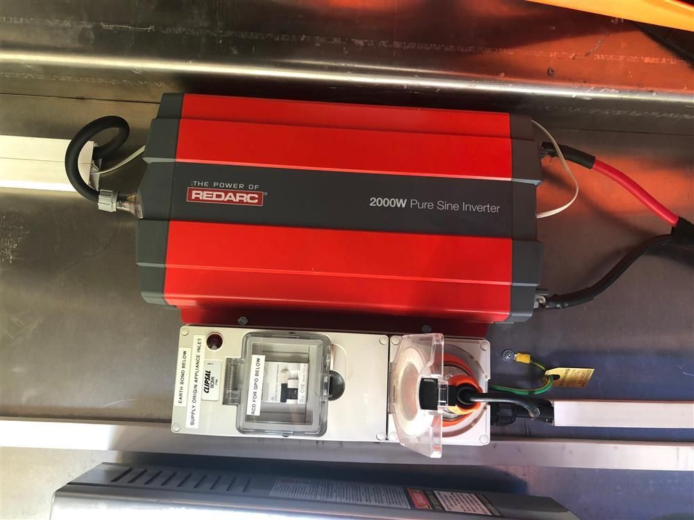 A red power inverter is sitting on a stainless steel surface