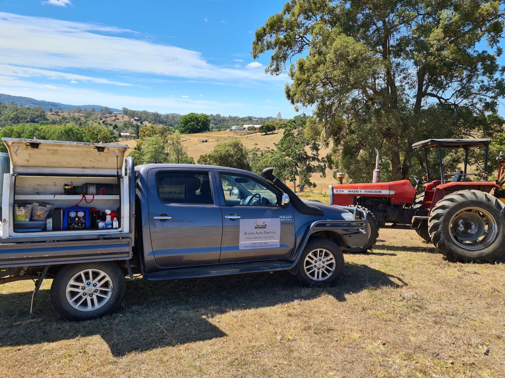A truck is parked next to a tractor in a field.