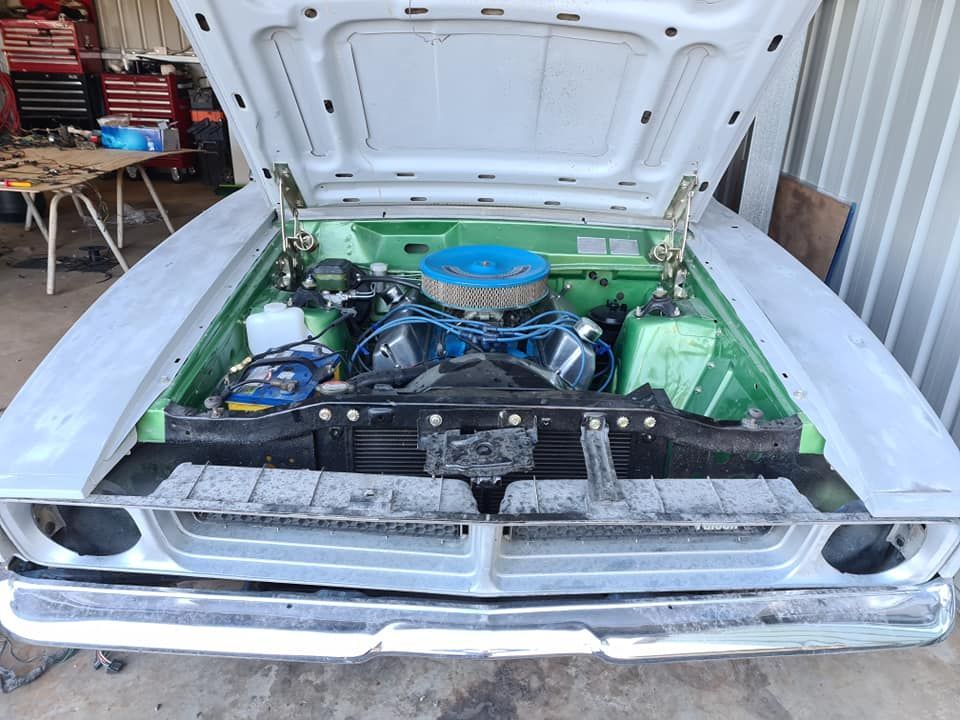 A green and white car with the hood open
