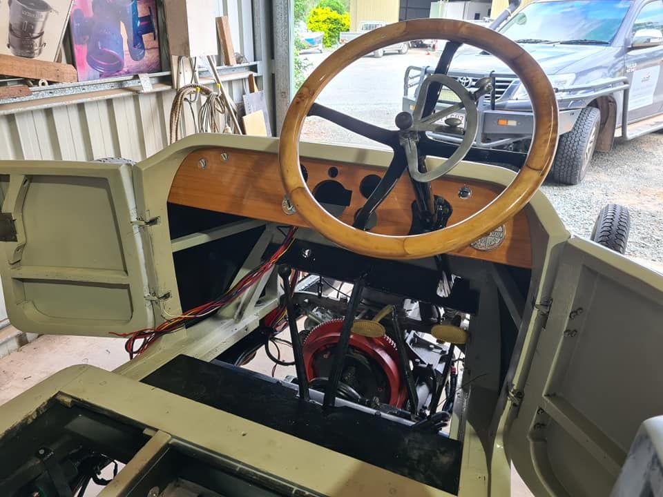 A car with a wooden steering wheel is sitting in a garage.