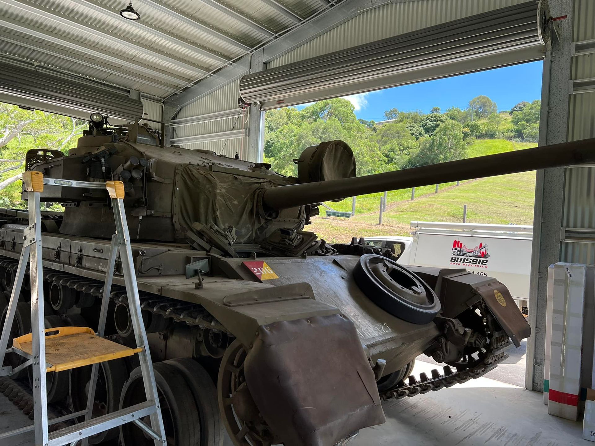A tank is sitting in a garage with the door open.