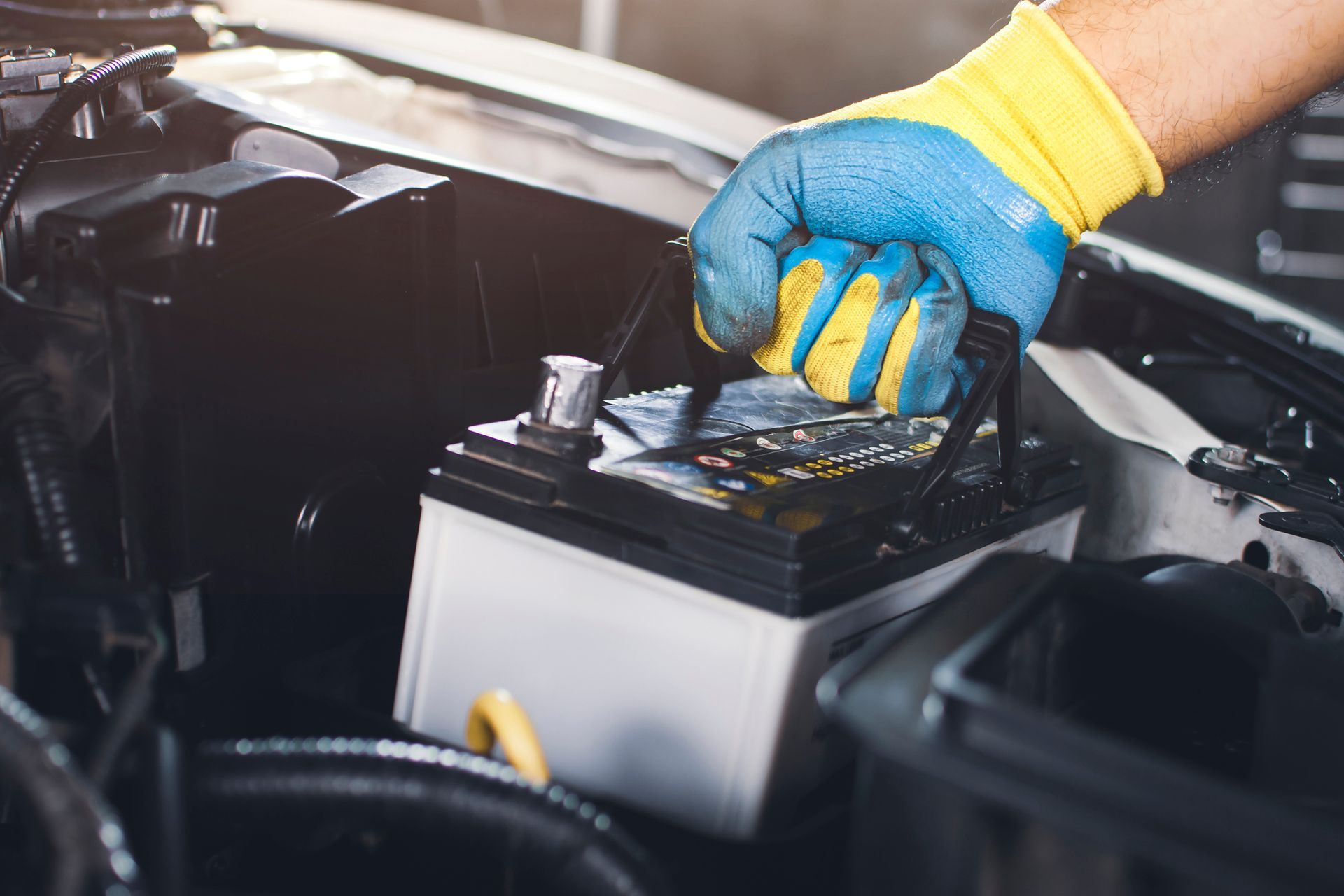 A person is holding a screwdriver over a car battery.