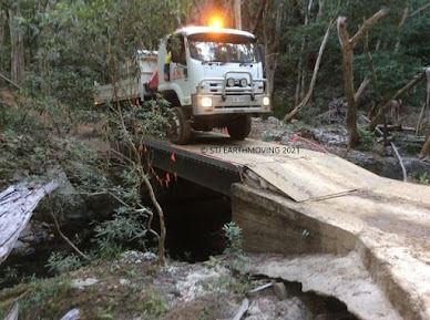 A Truck is Driving Over a Bridge in the Woods — STJ Earthmoving in Mareeba, QLD