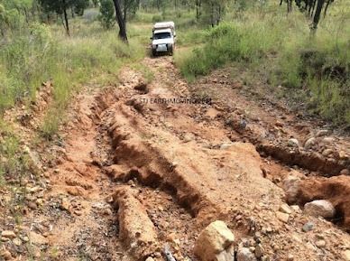 A White Suv is Driving Down a Muddy Dirt Road — STJ Earthmoving in Mareeba, QLD