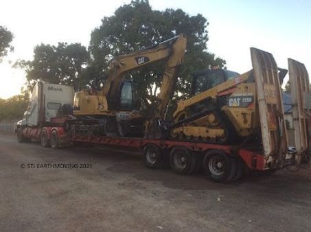 A Cat Excavator is Being Transported on a Flatbed Trailer — STJ Earthmoving in Mareeba, QLD