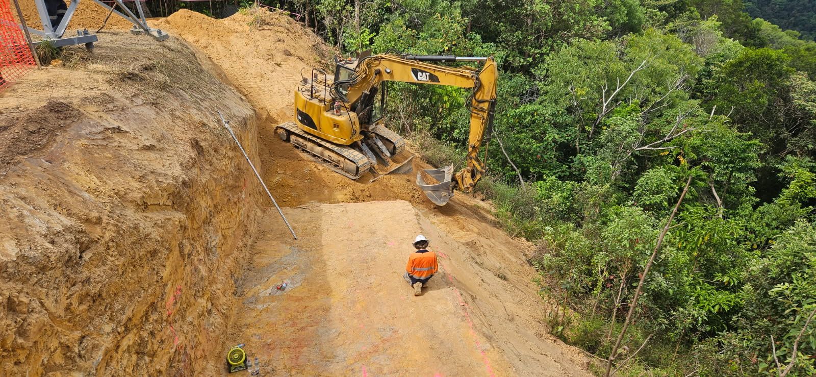 A Yellow Excavator Working on a Dirt Hillside — STJ Earthmoving in Mareeba, QLD