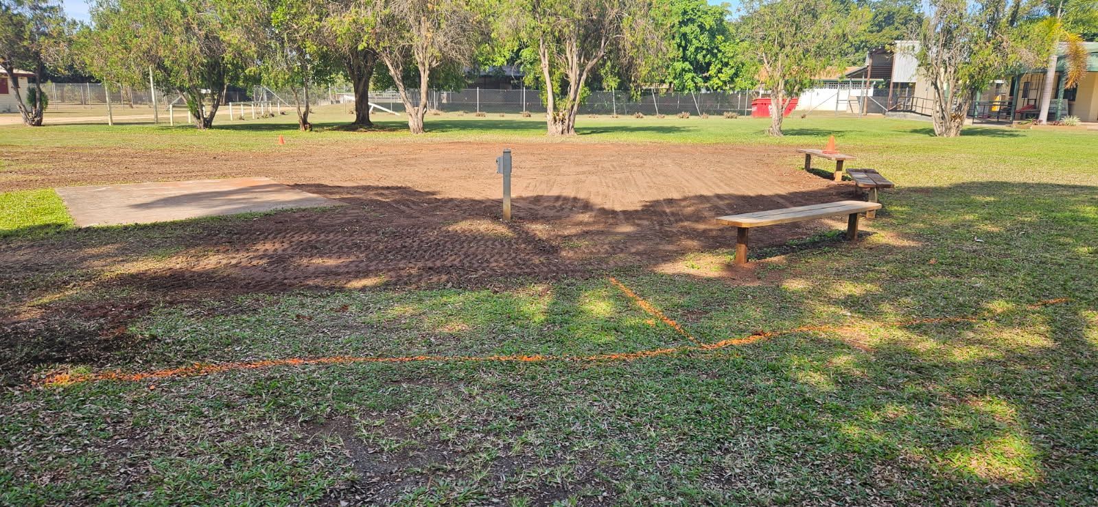 A Park With Trees, Grass, a Bench, and a Wooden Post Under a Bright Sky — STJ Earthmoving in Mareeba, QLD