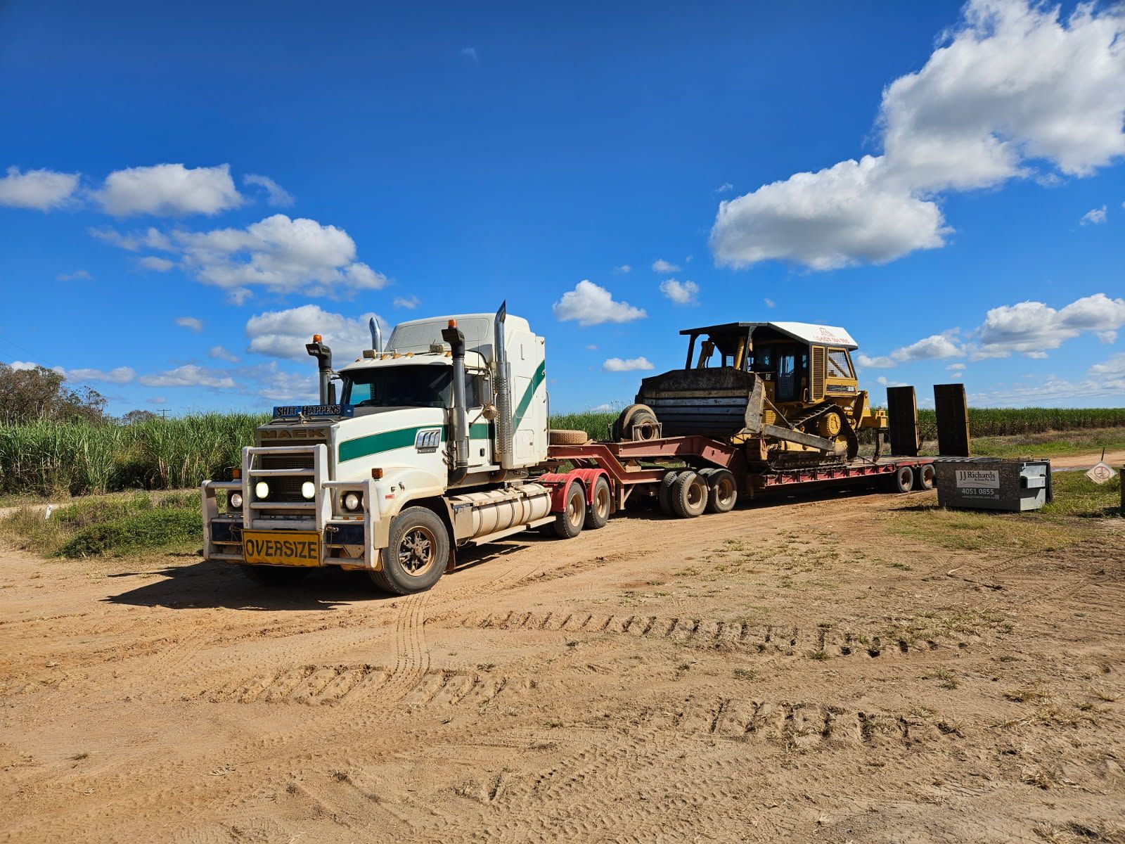 Truck Hauling a Dozer on a Trailer Along a Dirt Road — STJ Earthmoving in Mareeba, QLD