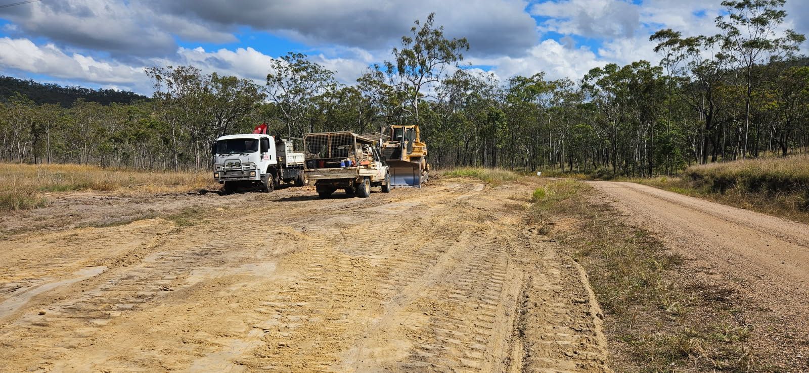 Dirt Road With Construction Vehicles in a Field — STJ Earthmoving in Mareeba, QLD