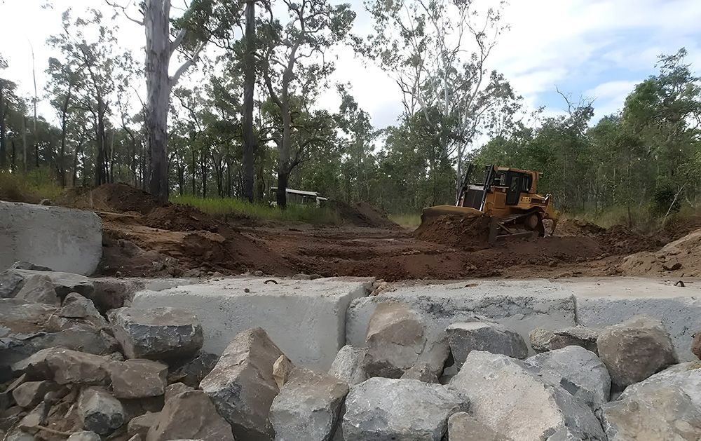 Bulldozer Clearing Earth Near Large Concrete Blocks