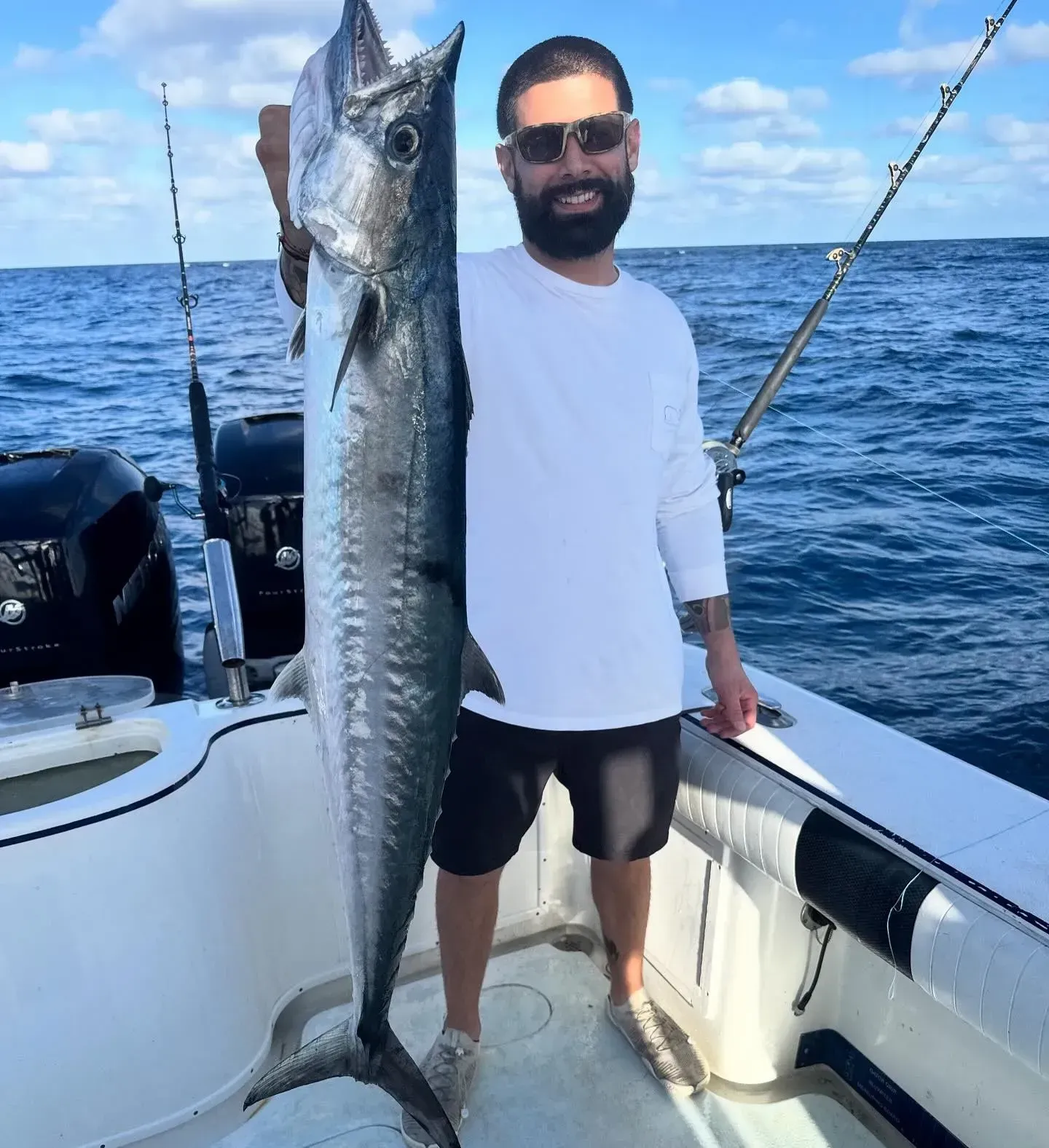 A man is standing on a boat holding a large fish