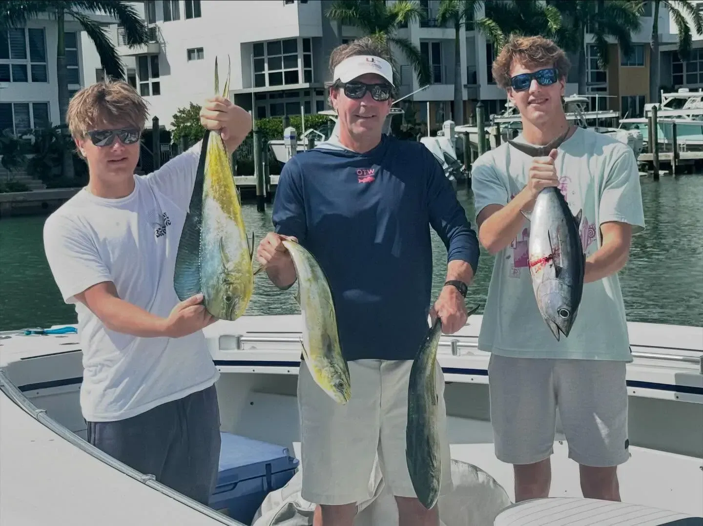 Three men are standing on a boat holding fish