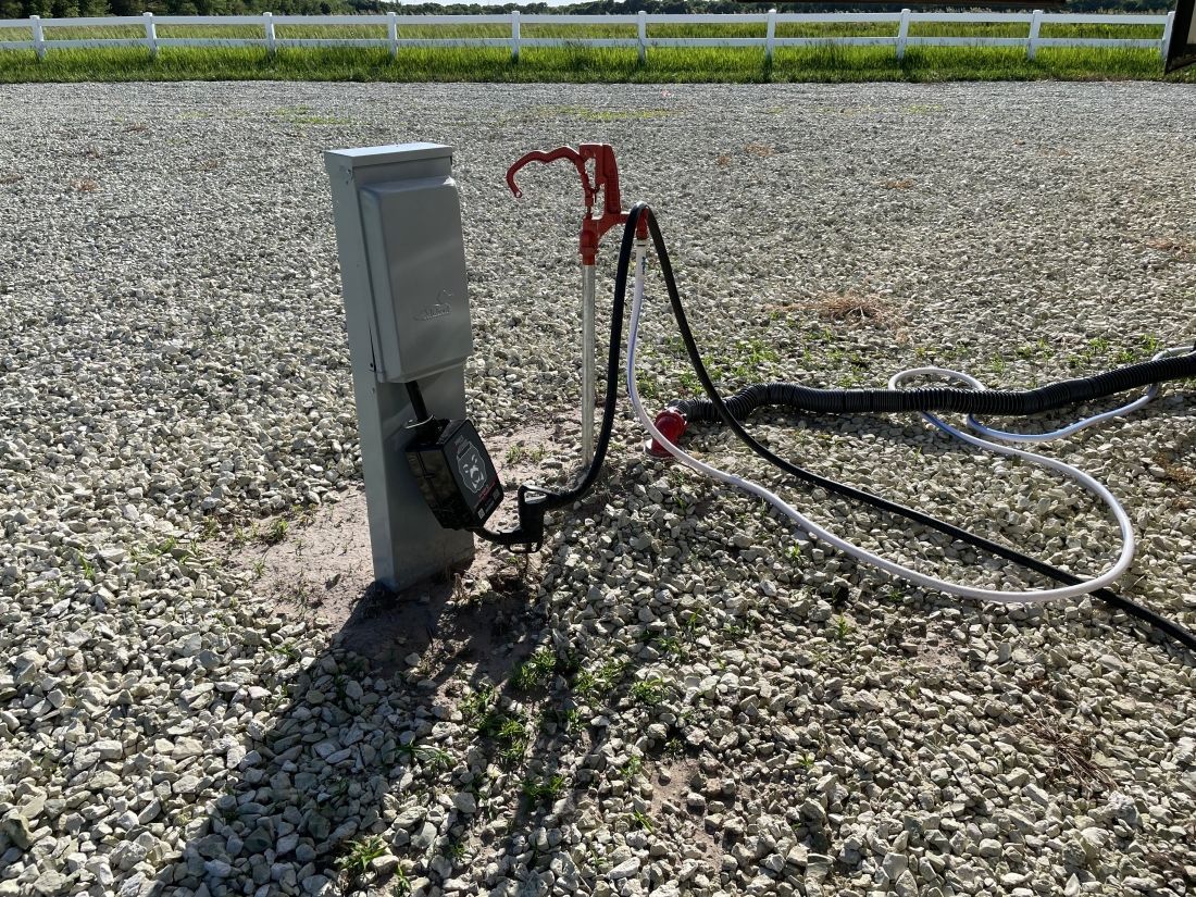 A rv is parked in a gravel lot next to a power outlet.