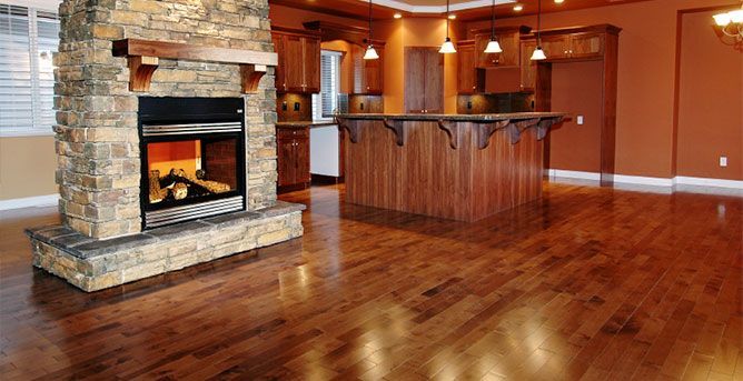Luxury hardwood flooring in a modern home with a stone fireplace and elegant kitchen.