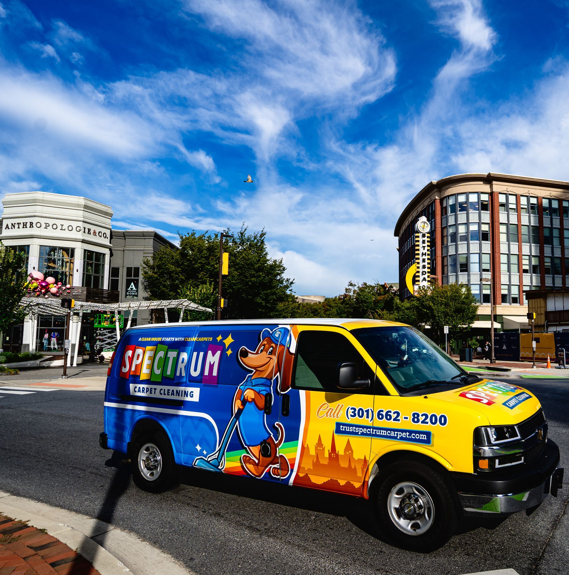 A blue van is parked in front of a brick building.