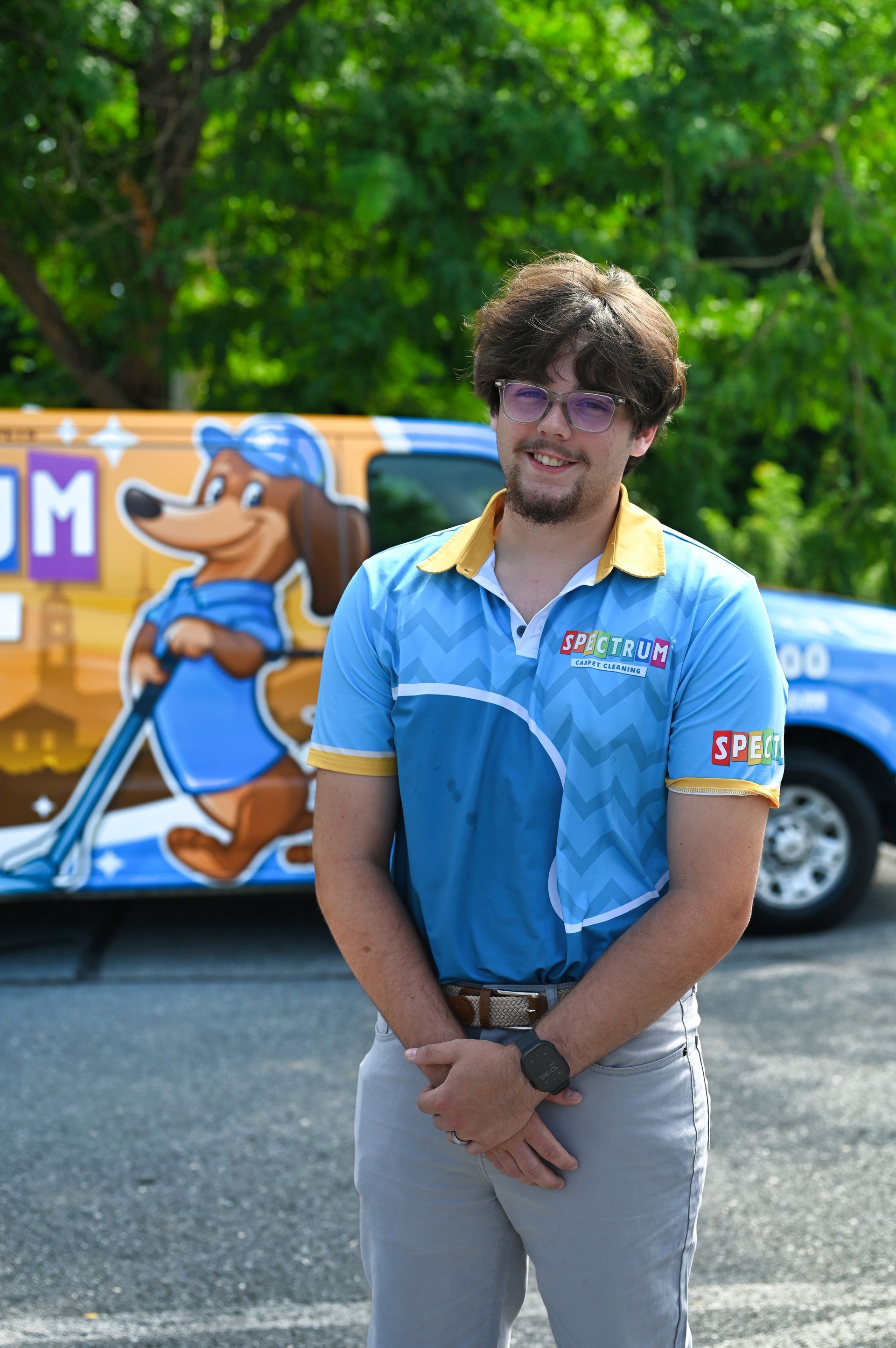 A young man is standing in front of a blue van.