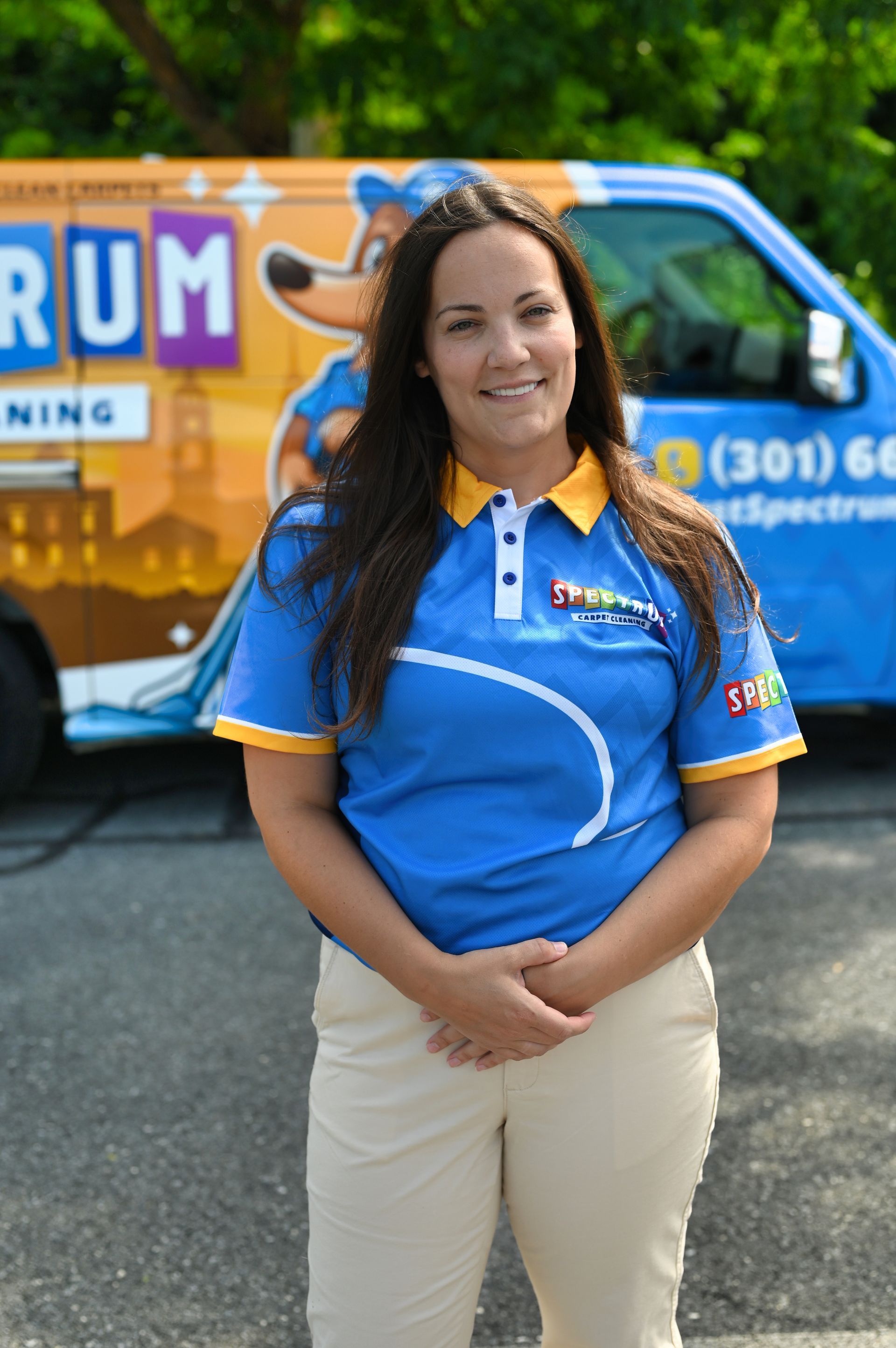 A woman is standing in front of a blue truck in a parking lot.