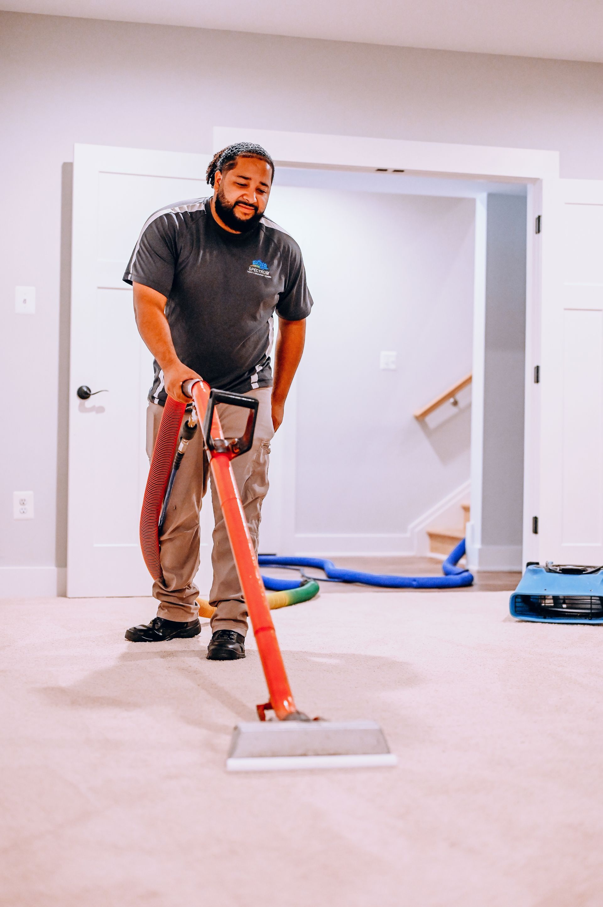 A man is using a vacuum cleaner to clean a carpet in a room.