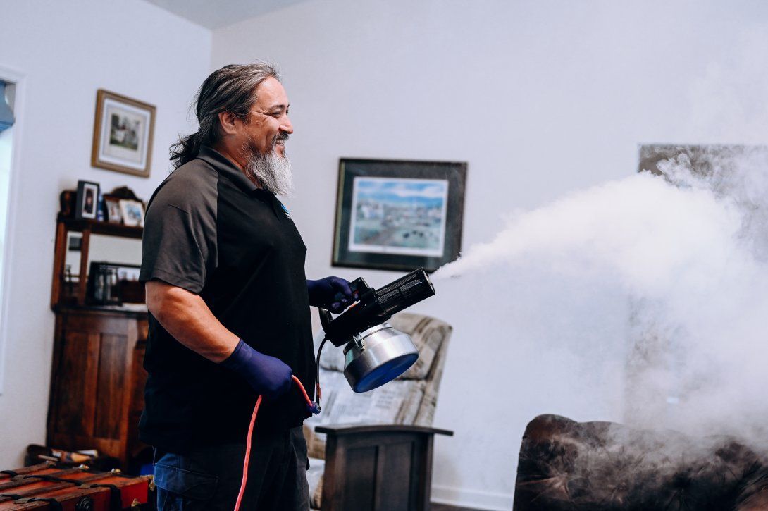 Expert technician using an advanced fogging system for deep odor removal in home furniture.