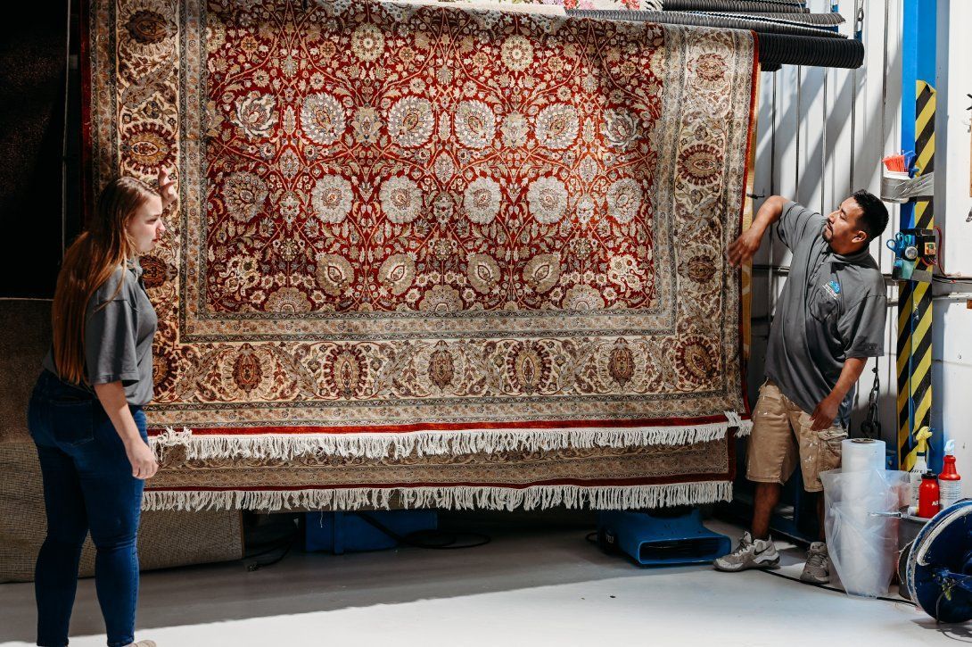 Spectrum Carpet Cleaning technicians handling an Oriental rug for professional deep cleaning.