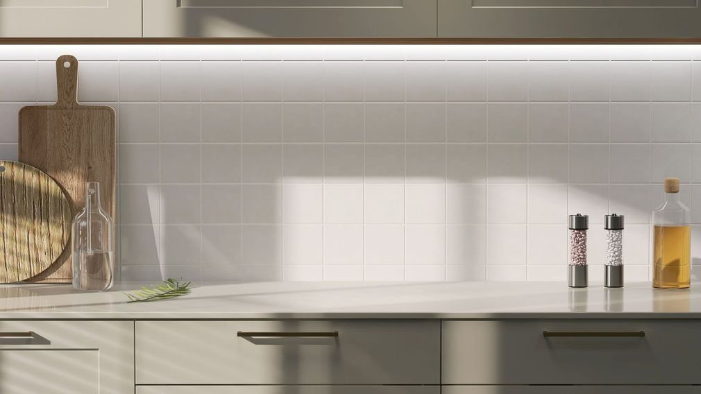 Plan de travail de cuisine avec planches à découper, épices et bouteille d'huile d'olive, éclairé par un plafonnier.