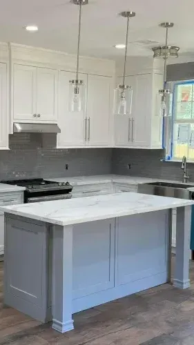 A kitchen with white cabinets and a large island in the middle.