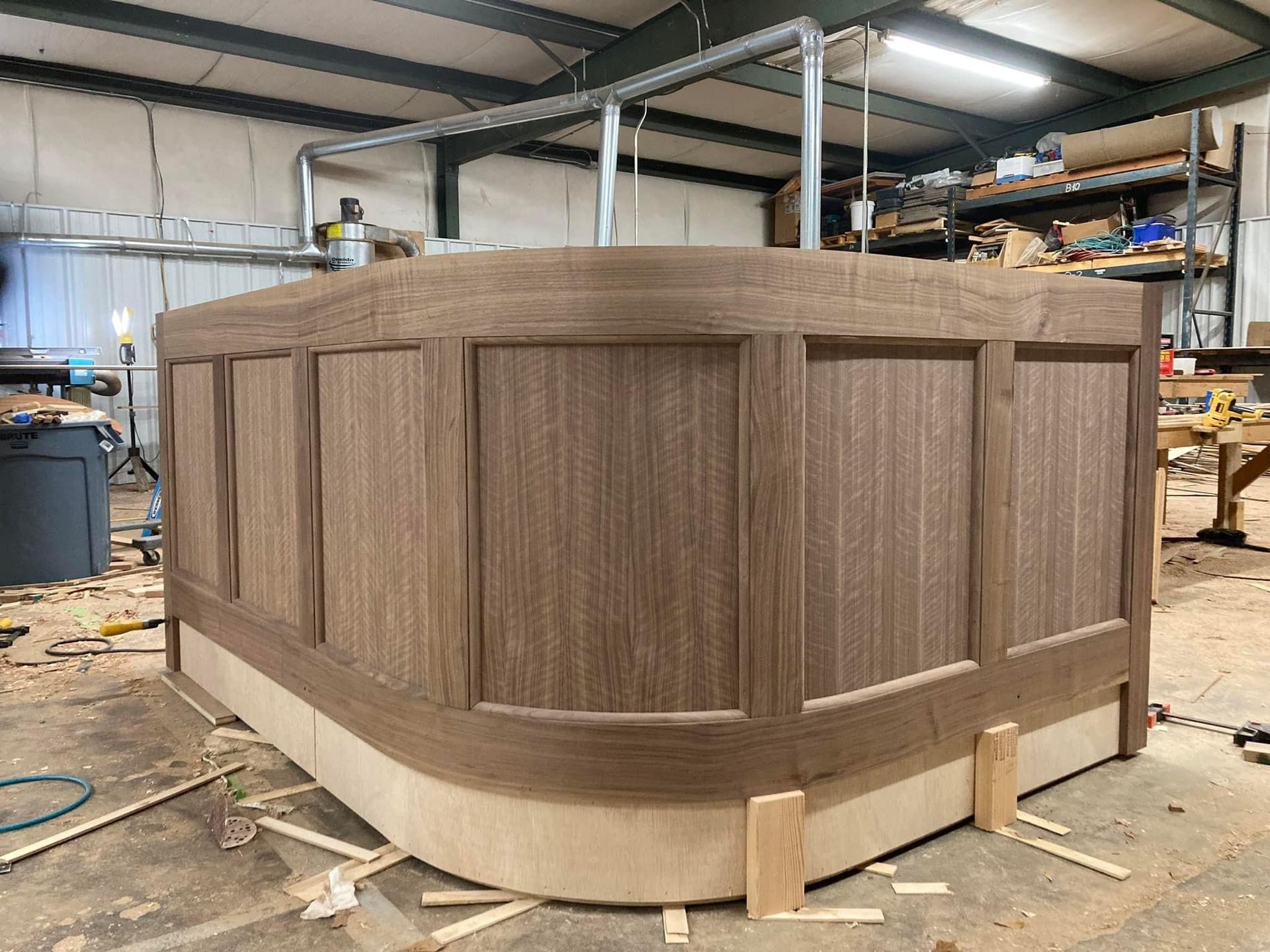 Custom-built curved wood panel bar in workshop, handcrafted by A&J Remodel and Construction for a high-end interior installation