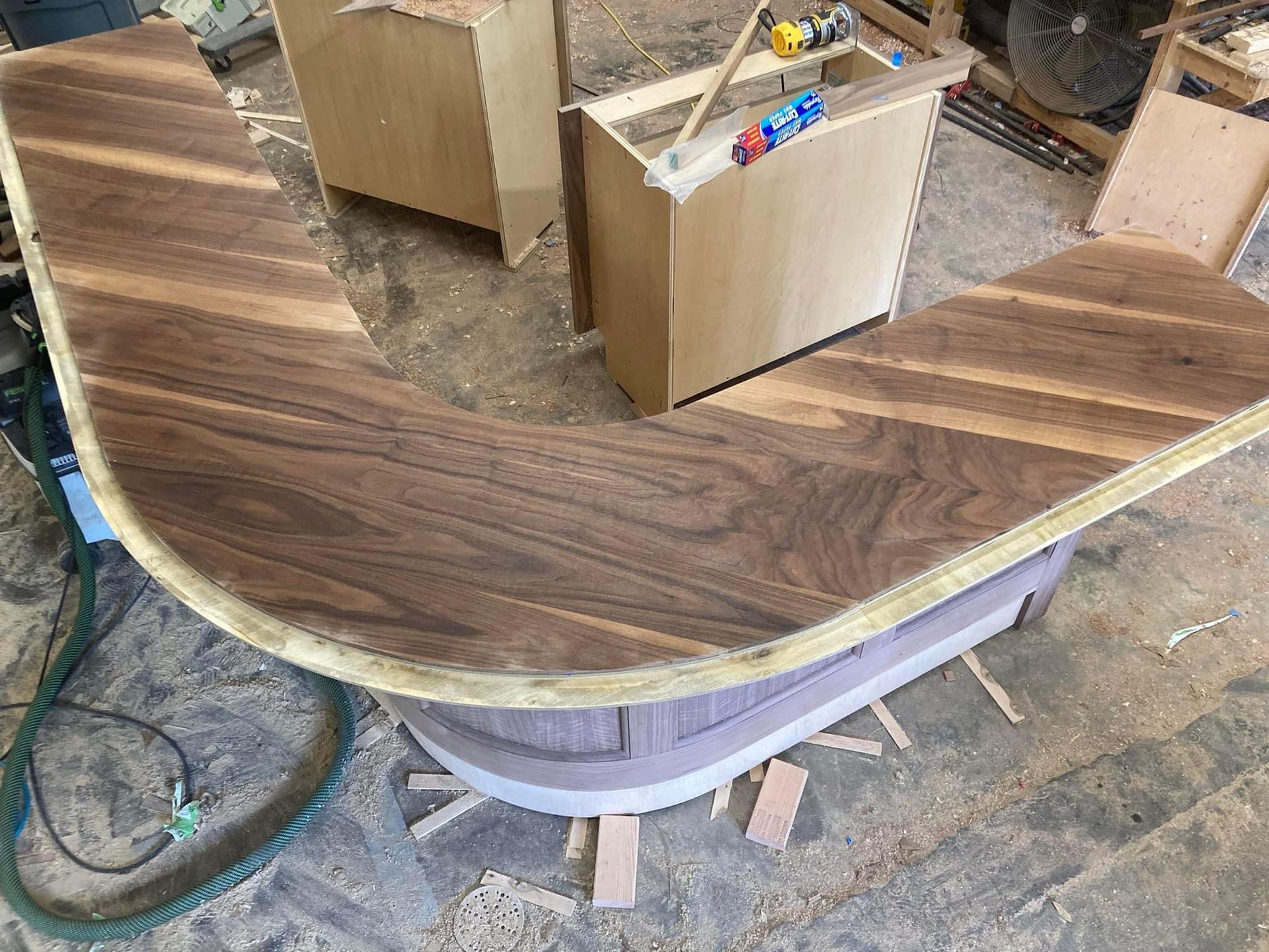 Overhead view of custom U-shaped wooden bar top with rich walnut grain, crafted by A&J Remodel and Construction during workshop fabrication