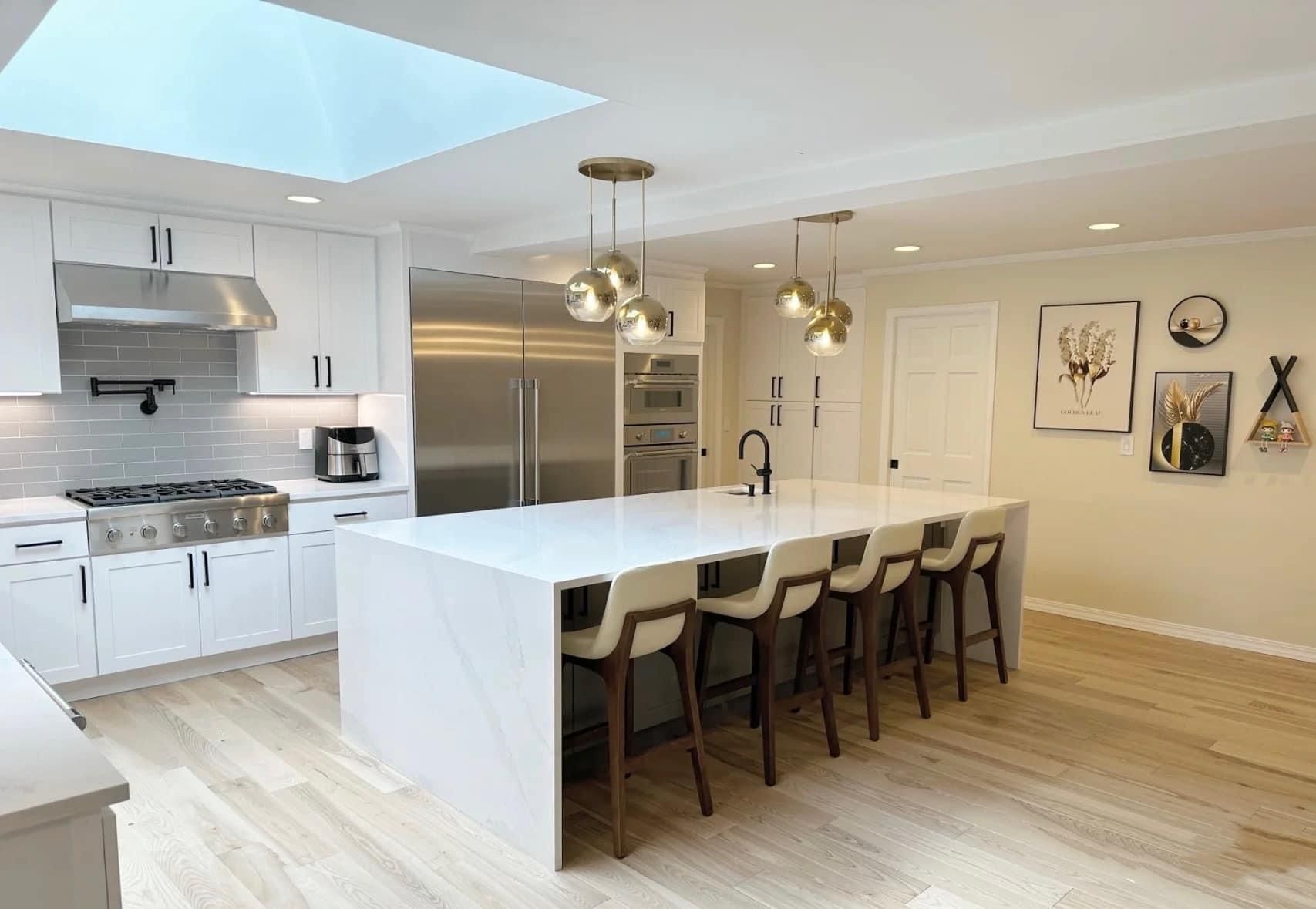 Modern white kitchen with light wood flooring and a central island, designed by A&J Remodel and Construction
