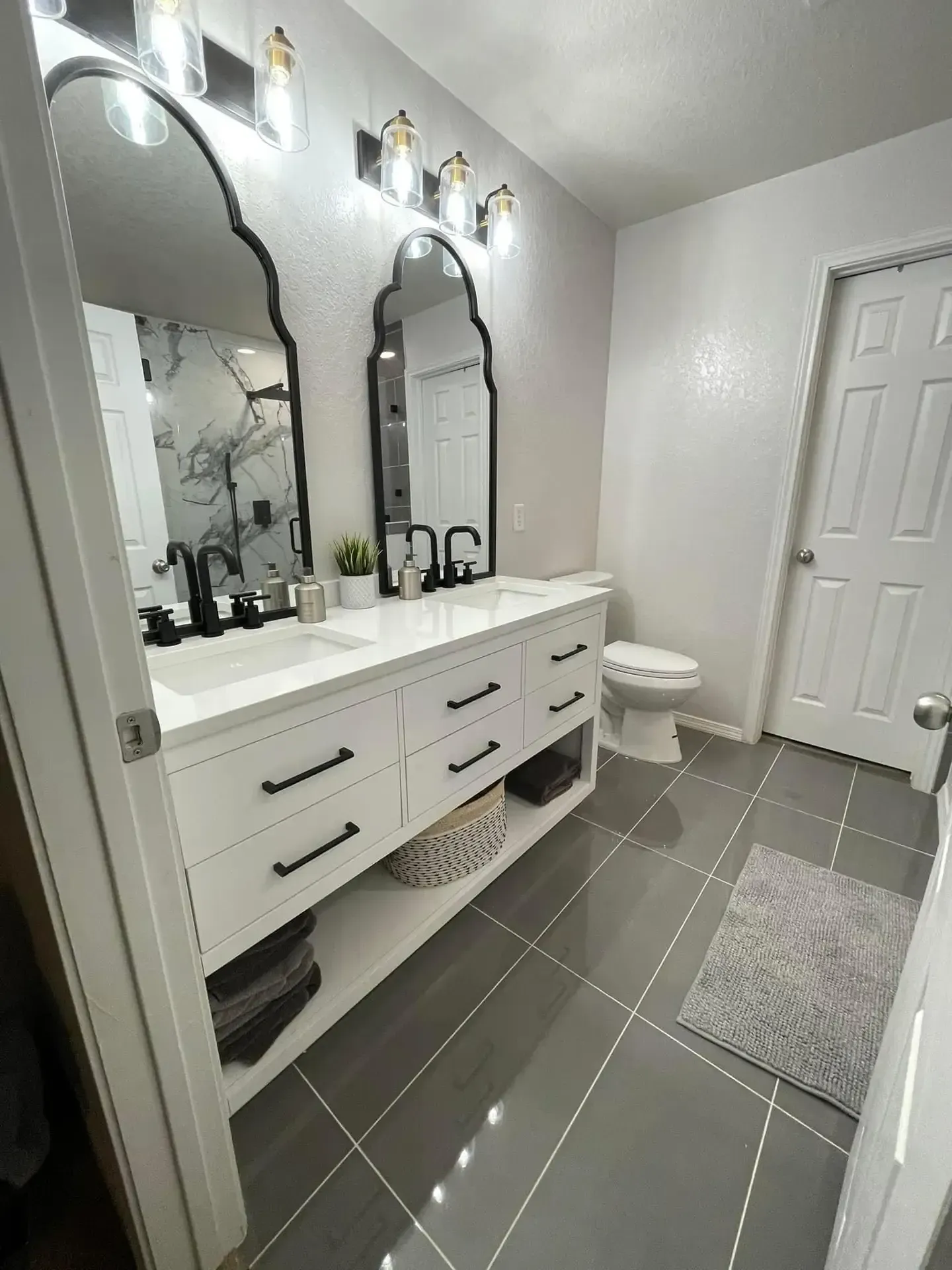 A bathroom with two sinks , a toilet , and two mirrors.