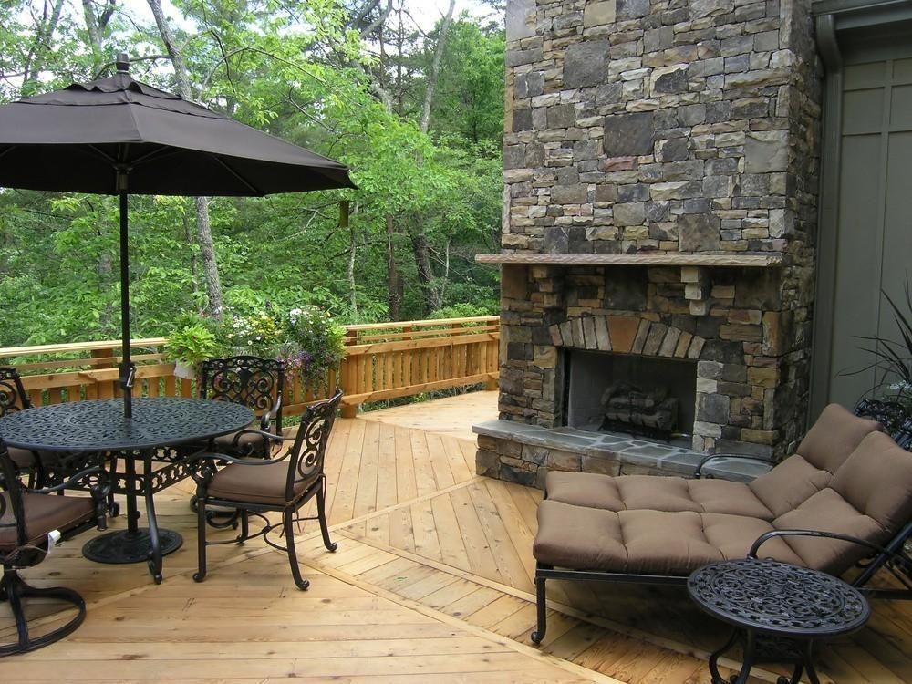 A wooden deck with a table and chairs and a fireplace