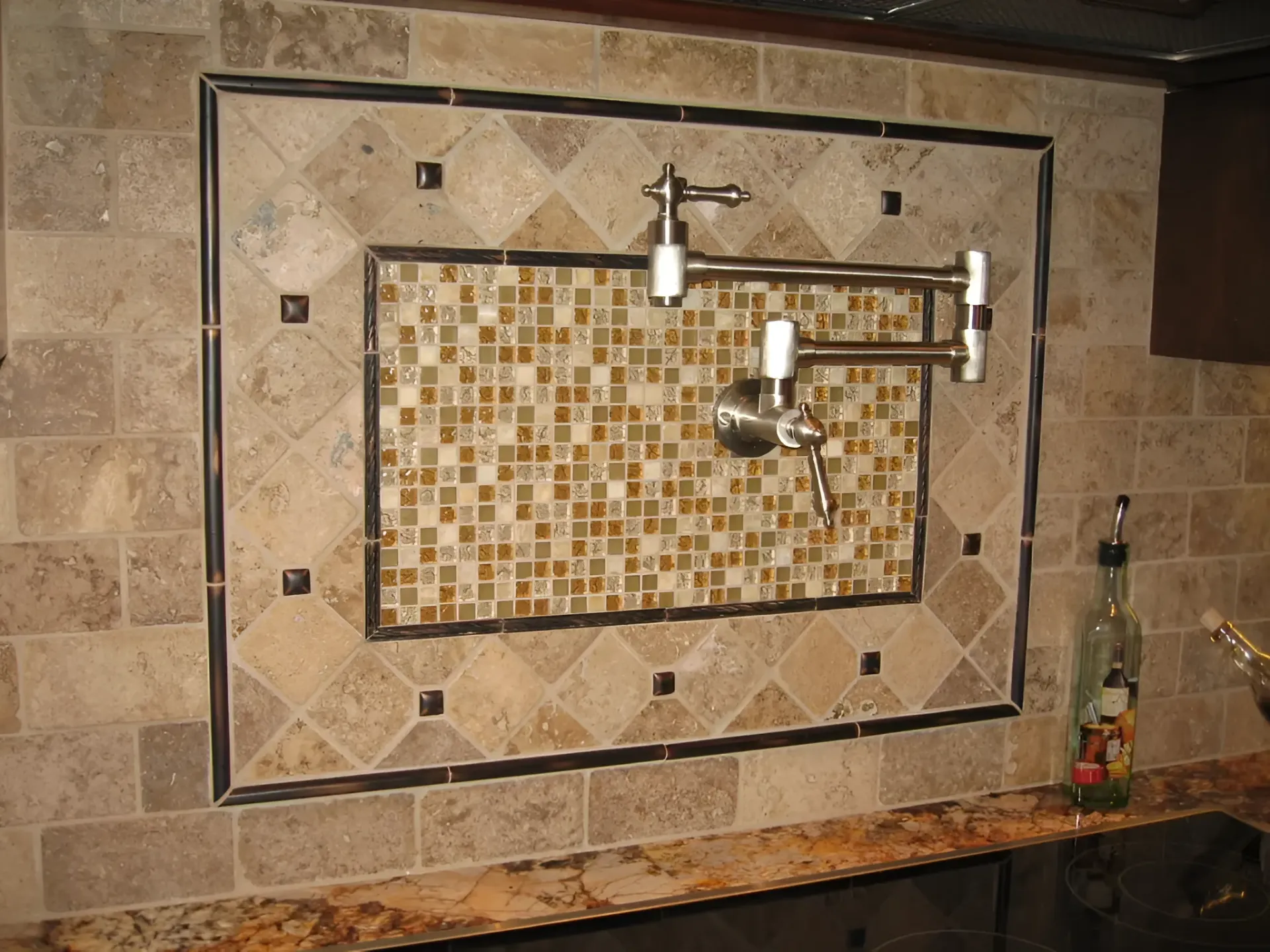 A wall-mounted pot filler faucet on a backsplash of decorative tiles.