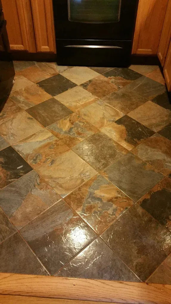 Diamond-patterned slate tile floor with various earth-tone colors in front of a black oven.