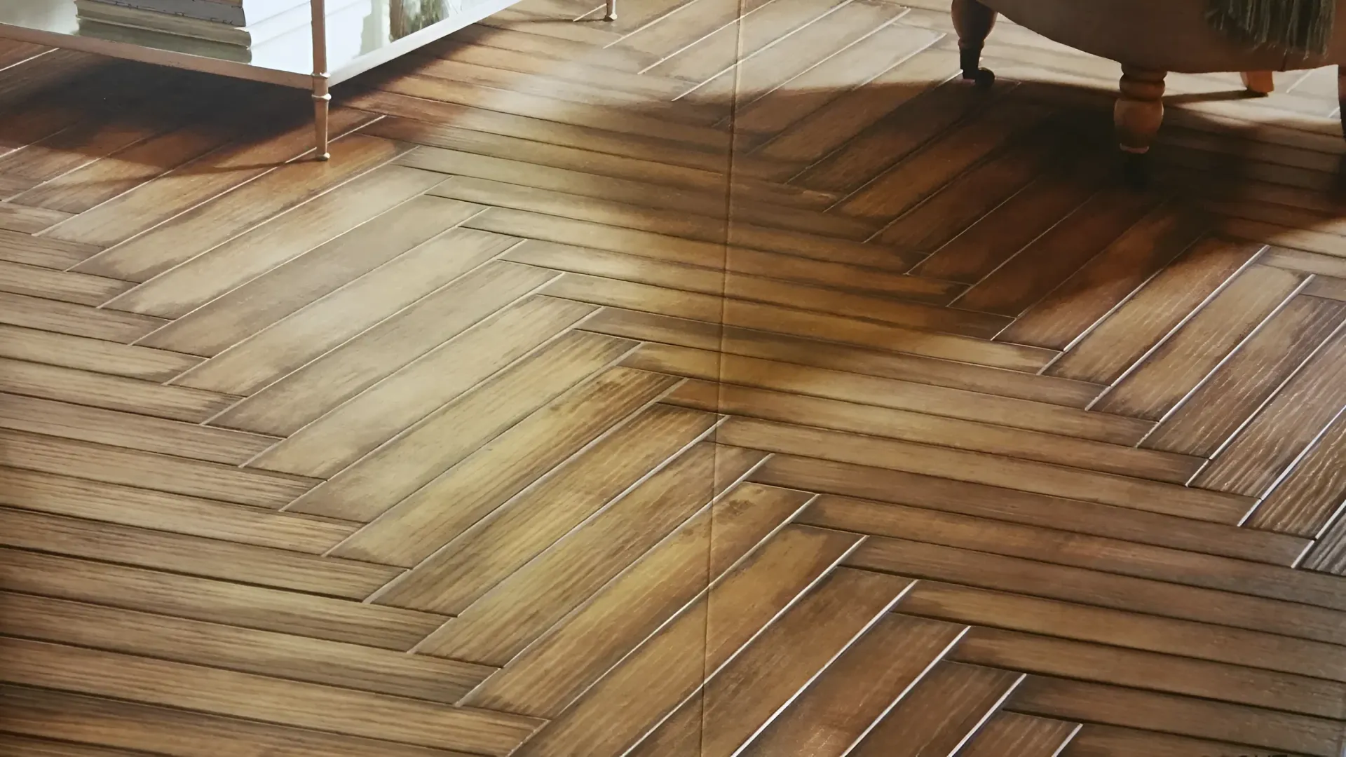 Herringbone pattern wood floor with furniture leg in the corner, bookshelves in the background.