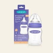 Biberón de leche materna Lansinoh junto a su envase. Biberón transparente con aro y tetina morados.